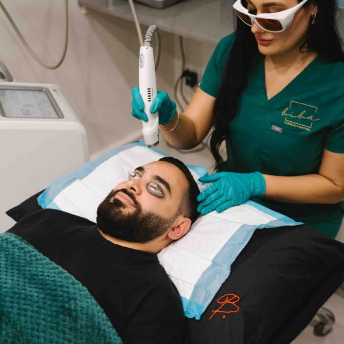 Cosmetic nurse performing skin needling on a male client at a skin care clinic.
